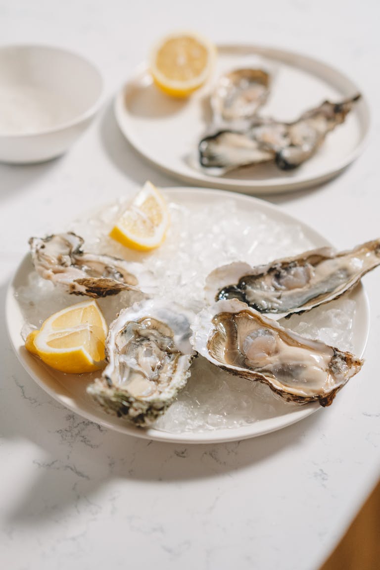 zinc and hormones: Close-up of fresh raw oysters on ice with lemon wedges on a serving plate, perfect for seafood enthusiasts.