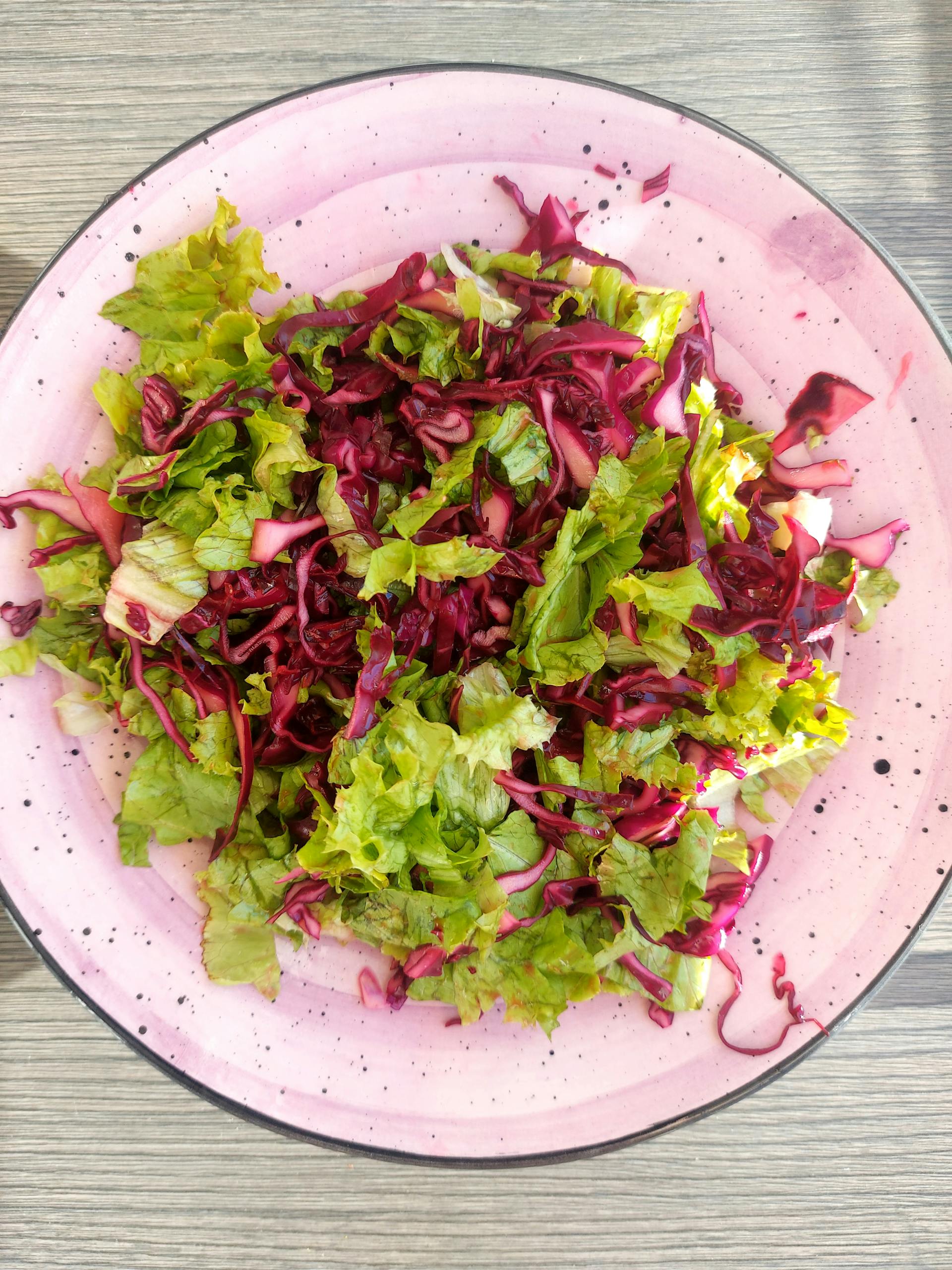 Brain-Healthy Grocery List: Healthy fresh mixed salad of greens and red cabbage on a pink plate.