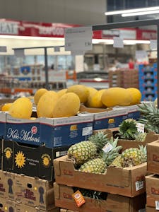 Healthy Costco Snacks: Selection of fresh melons and pineapples on display at a grocery store.