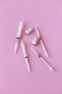 not losing weight on glp-1: Syringes and vials arranged on a pink background for medical and healthcare concepts.