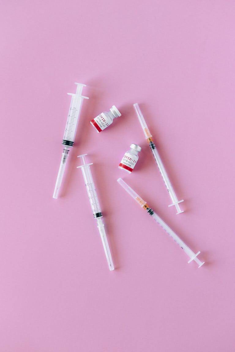 not losing weight on glp-1: Syringes and vials arranged on a pink background for medical and healthcare concepts.