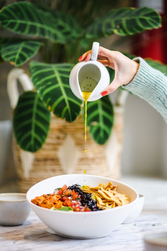 Healthiest Sweetgreen Orders: Vegan salad with fresh vegetables and chips being drizzled with olive oil.
