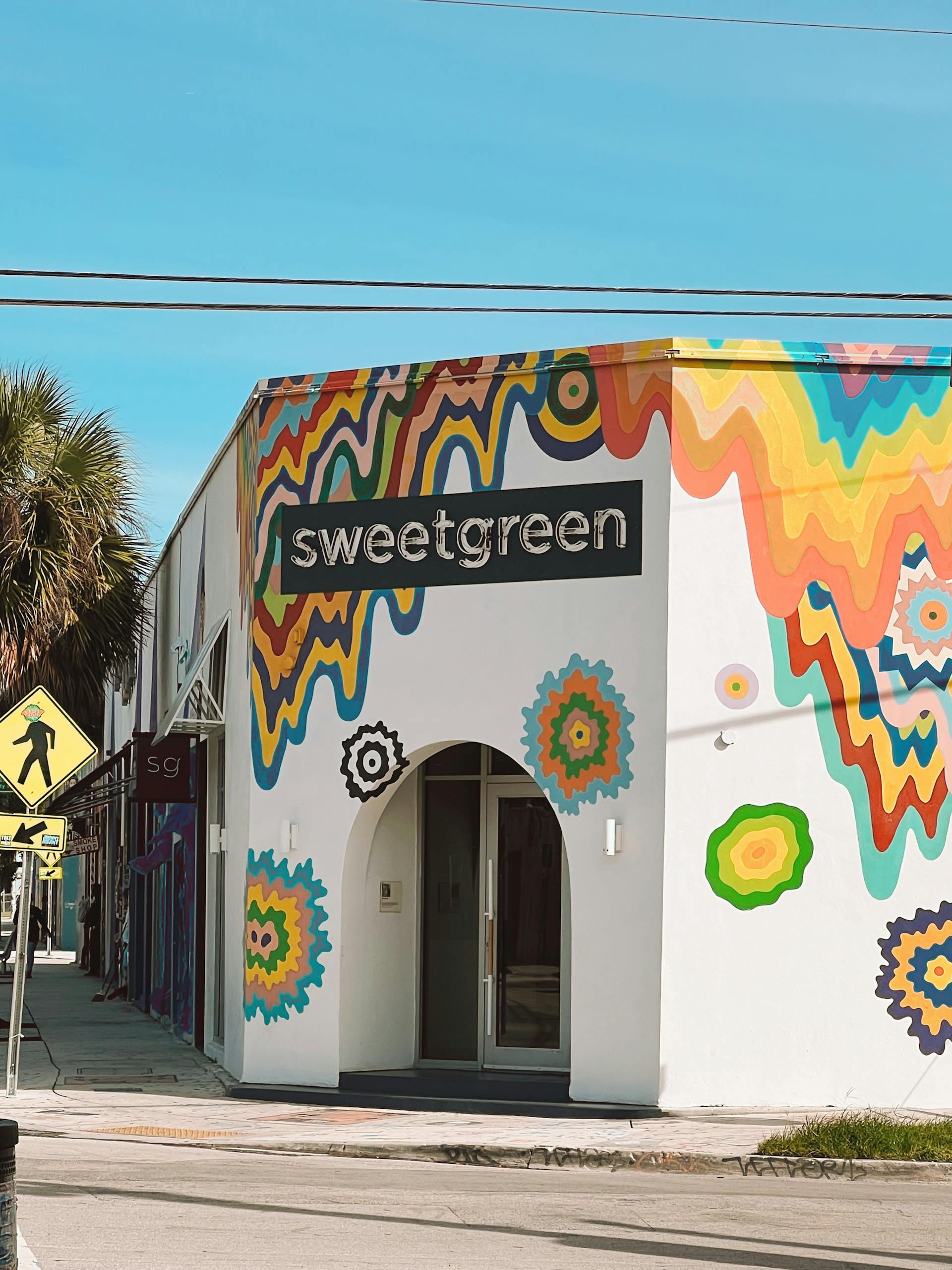 Healthiest Sweetgreen Orders: Vibrant Sweetgreen restaurant exterior with artistic mural in a sunny urban setting.
