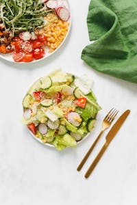How to Lose Weight Without Feeling Hungry: Healthy and colorful vegetarian salad with gold cutlery on white background, perfect for a nutritious meal.