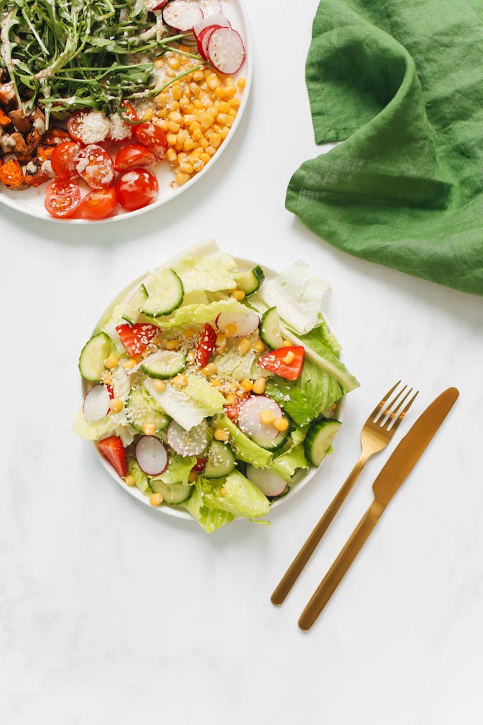 How to Lose Weight Without Feeling Hungry: Healthy and colorful vegetarian salad with gold cutlery on white background, perfect for a nutritious meal.