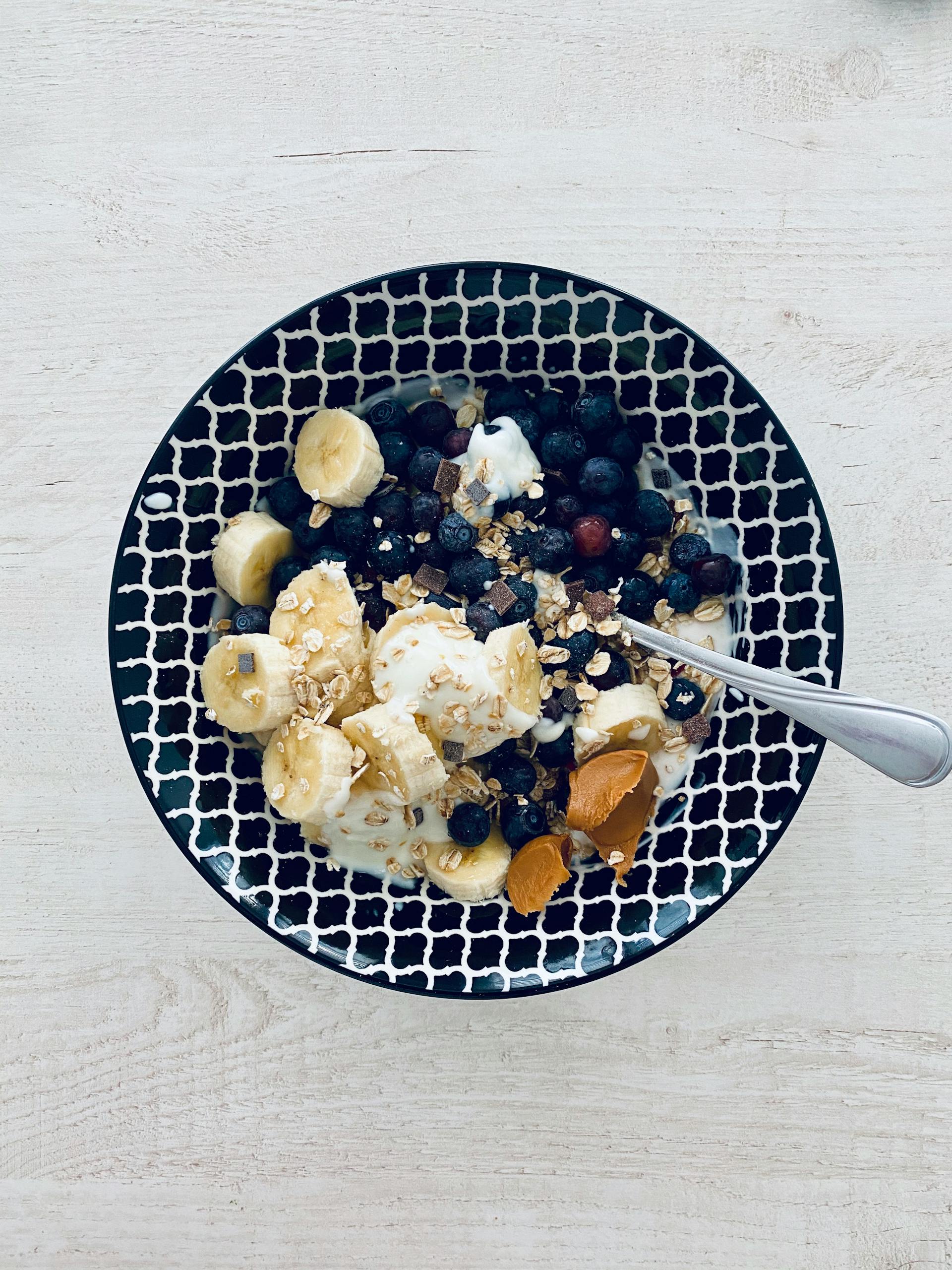 healthy eating myths: Top view of a nutritious breakfast bowl with bananas, berries, and granola.