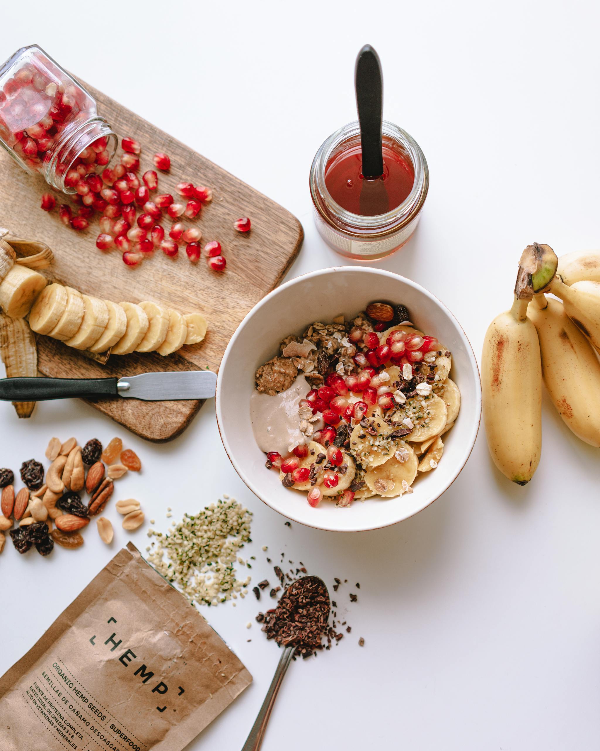 How to Lose Weight Without Feeling Hungry: Top view of a nutritious breakfast bowl with sliced bananas, pomegranate seeds, and nuts.