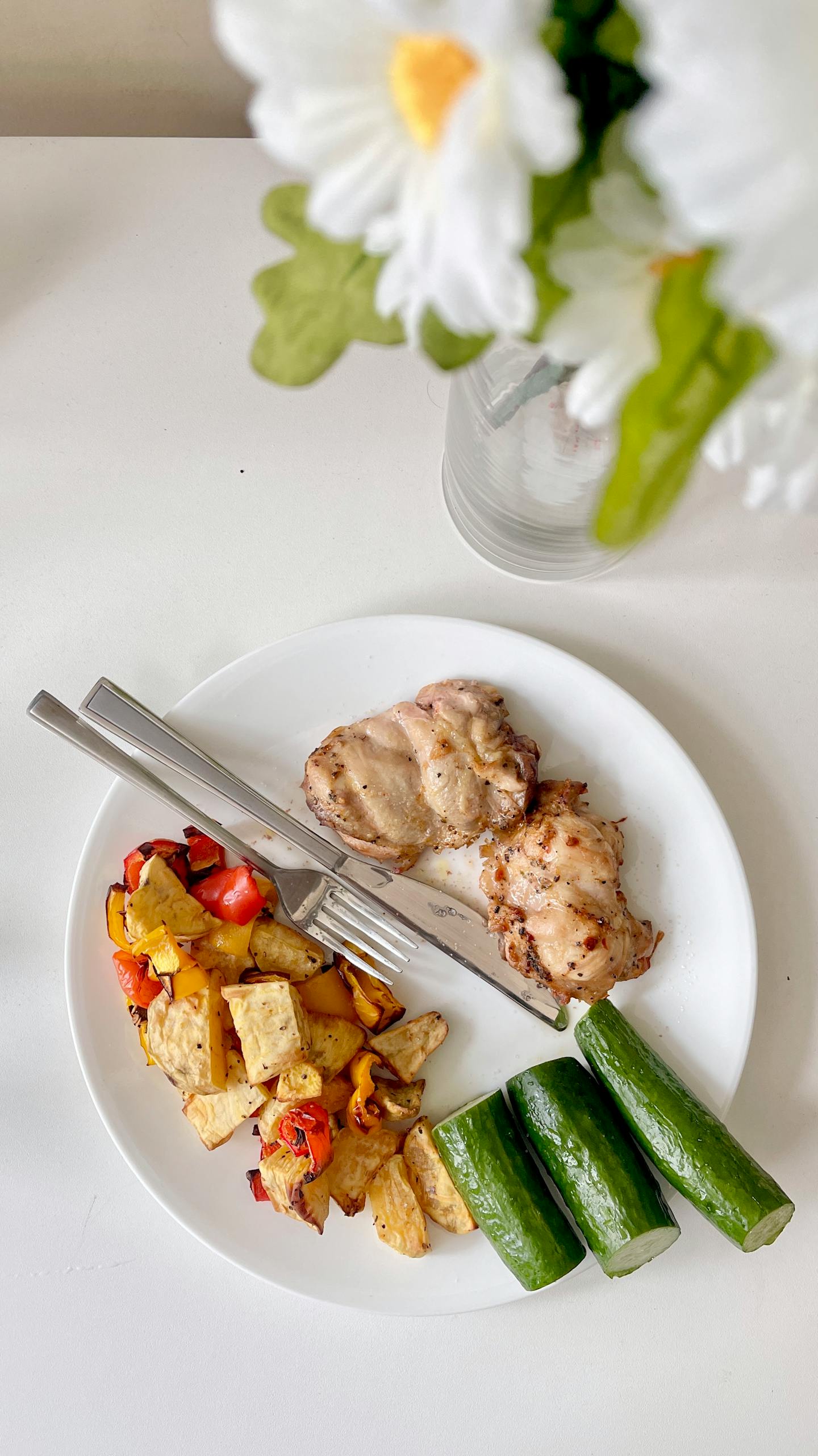 How to Lose Weight Without Feeling Hungry: Top view of a nutritious meal featuring grilled chicken, vegetables, and fresh cucumbers on a white plate.