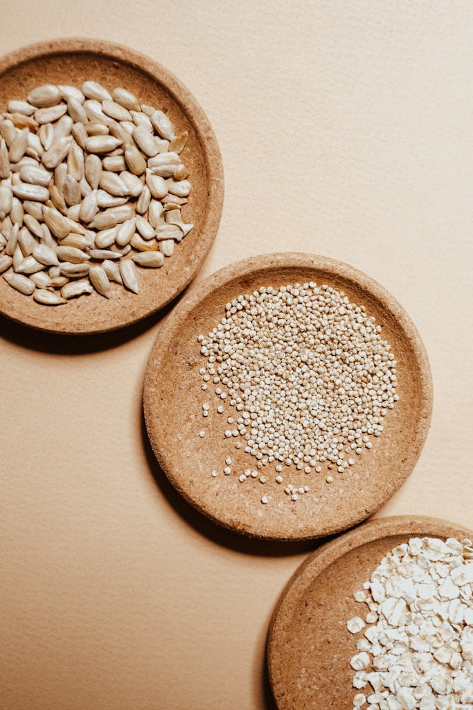 seed cycling for hormones: Top view of assorted seeds and grains in rustic bowls on a neutral background, ideal for healthy eating concepts.