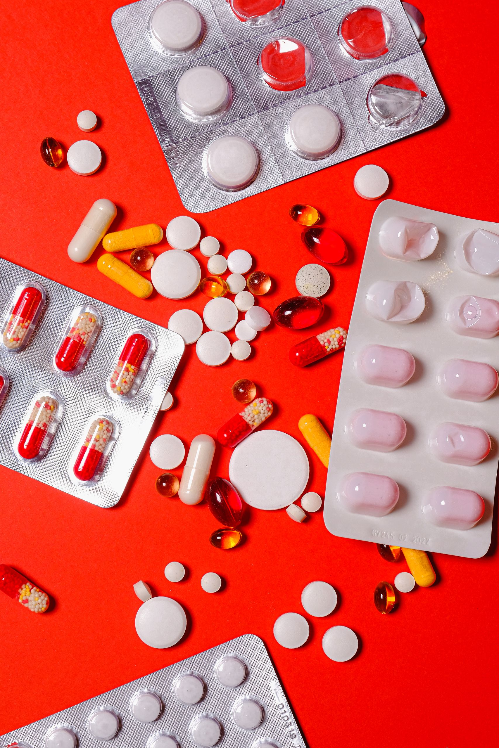 do you need a multivitamin: A close-up of various pills and capsules on a vibrant red background, highlighting healthcare and medicine.