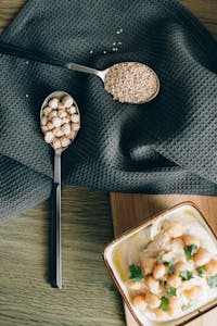 Easy Protein Swaps for Weight Loss: A stylish flat lay of hummus with chickpeas and sesame seeds on a cloth background.