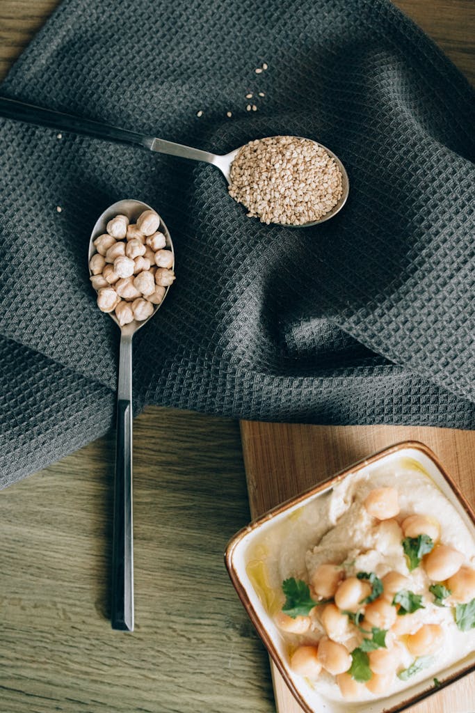 Easy Protein Swaps for Weight Loss: A stylish flat lay of hummus with chickpeas and sesame seeds on a cloth background.