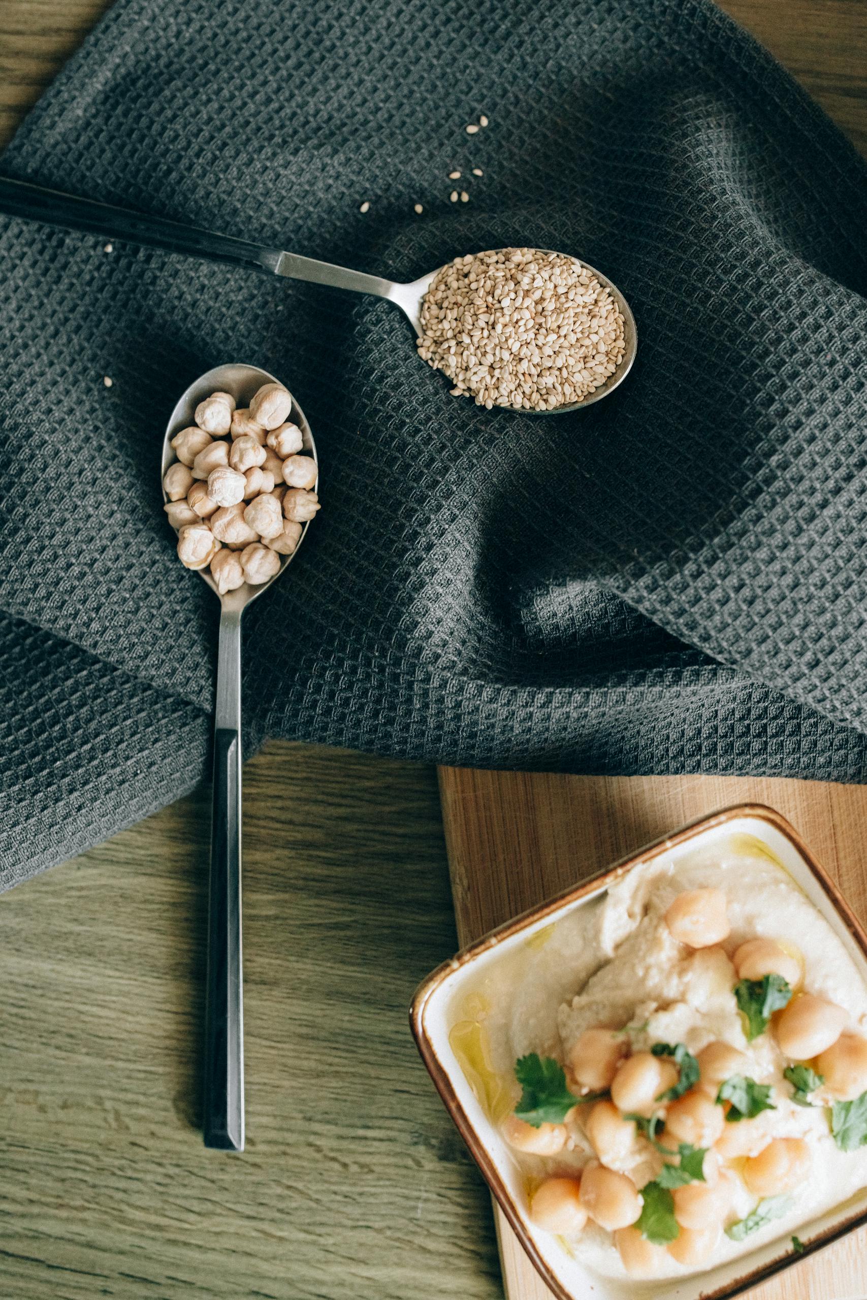 Easy Protein Swaps for Weight Loss: A stylish flat lay of hummus with chickpeas and sesame seeds on a cloth background.