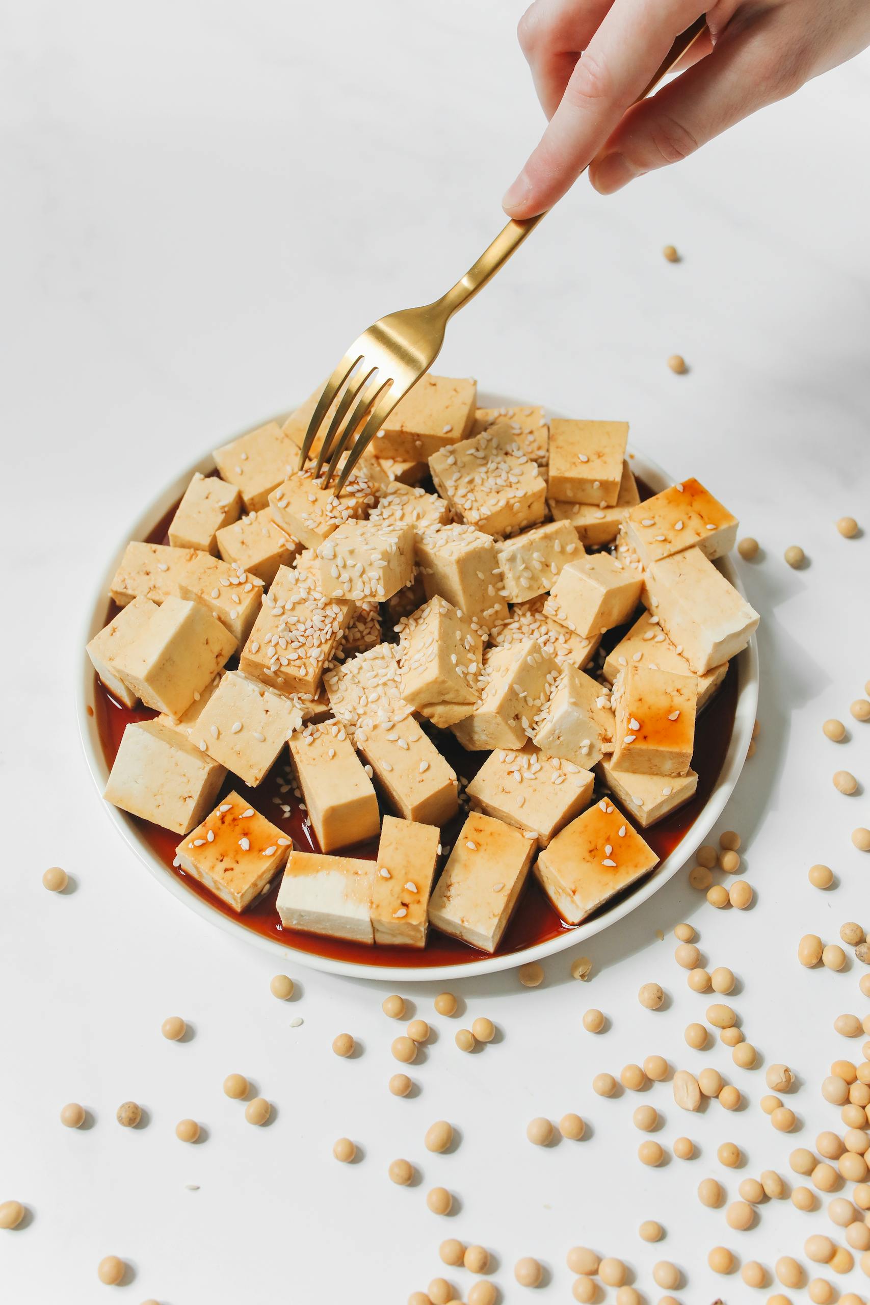 is soy bad for you? Appetizing tofu slices adorned with sesame, soy sauce and a golden fork ready to enjoy.