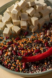 plant-based protein: Close-up of tofu cubes, chili pepper, and colorful beans on a plate.