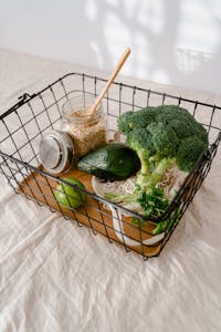 What Is the MIND Diet: Fresh broccoli, avocado, and oats ready for healthy meal preparations in a wire basket.
