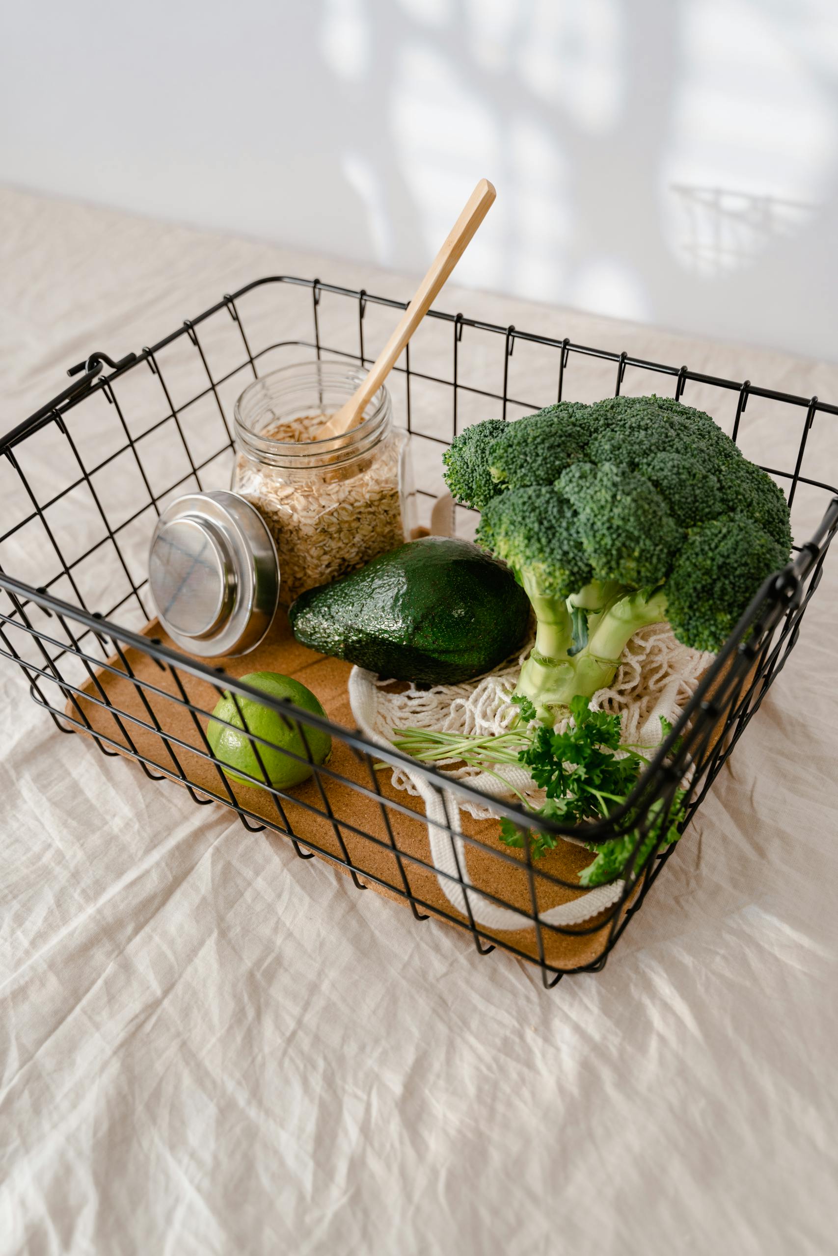 What Is the MIND Diet: Fresh broccoli, avocado, and oats ready for healthy meal preparations in a wire basket.