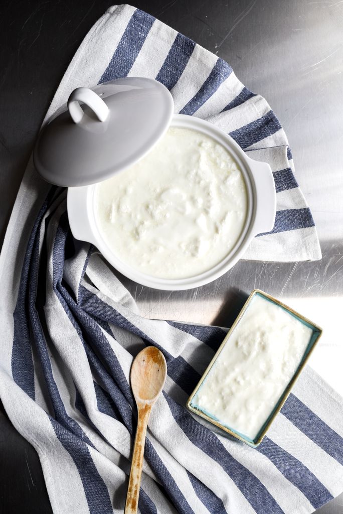 How to Introduce Allergens to Baby: Top view of homemade yogurt in a ceramic pot, styled with a wooden spoon and striped cloth.