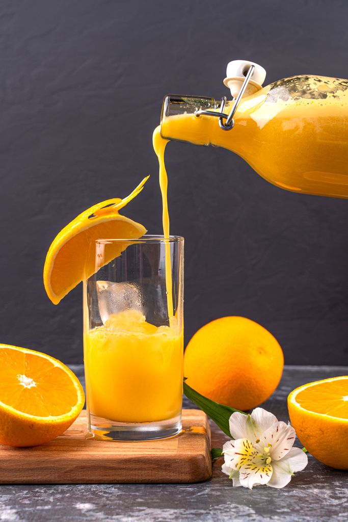 Vitamin C for immunity and colds: Vibrant orange juice poured into a glass surrounded by fresh oranges and a blossom.