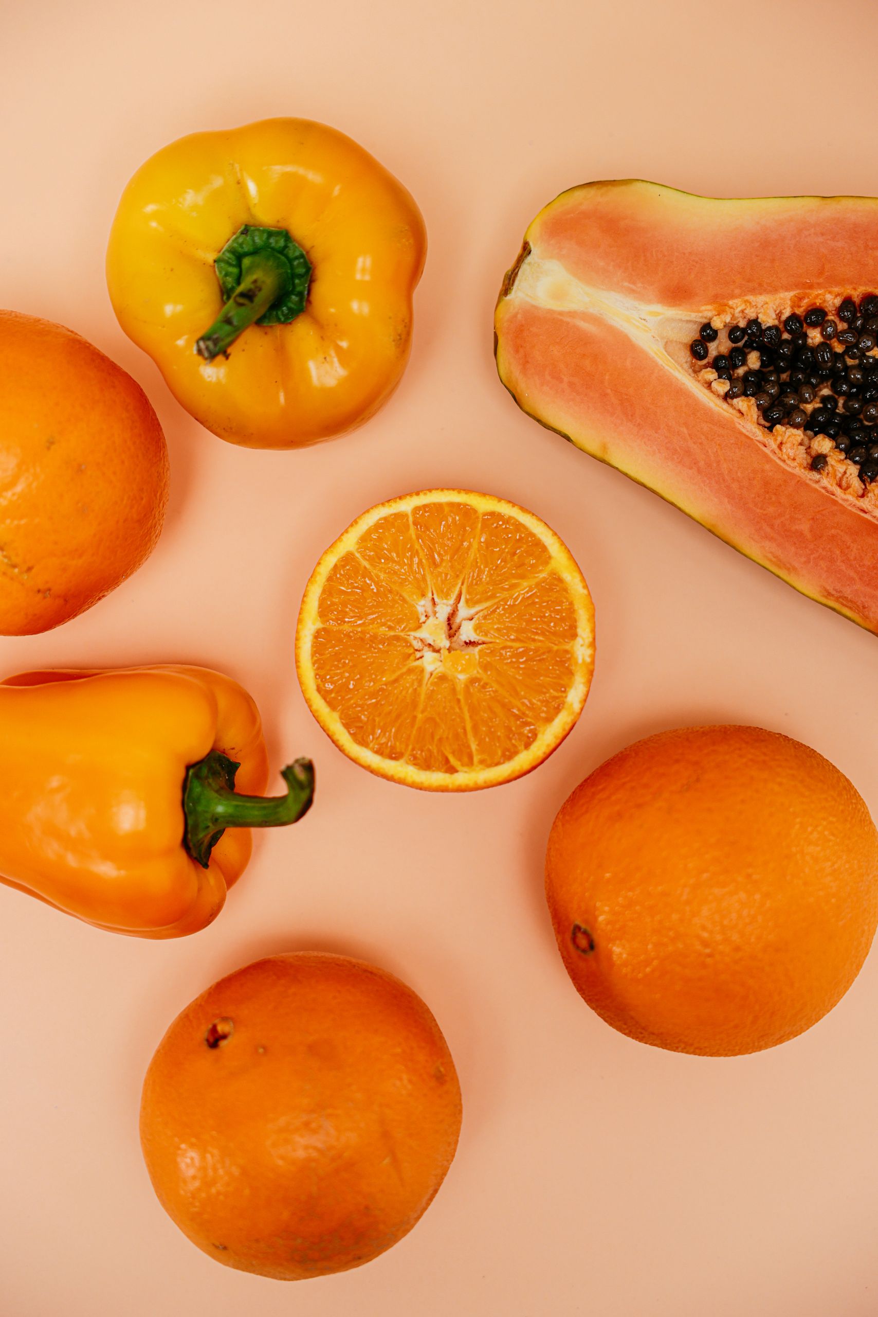 Vitamin C for immunity and colds: Vibrant top view of oranges, yellow peppers, and papaya on a warm background.