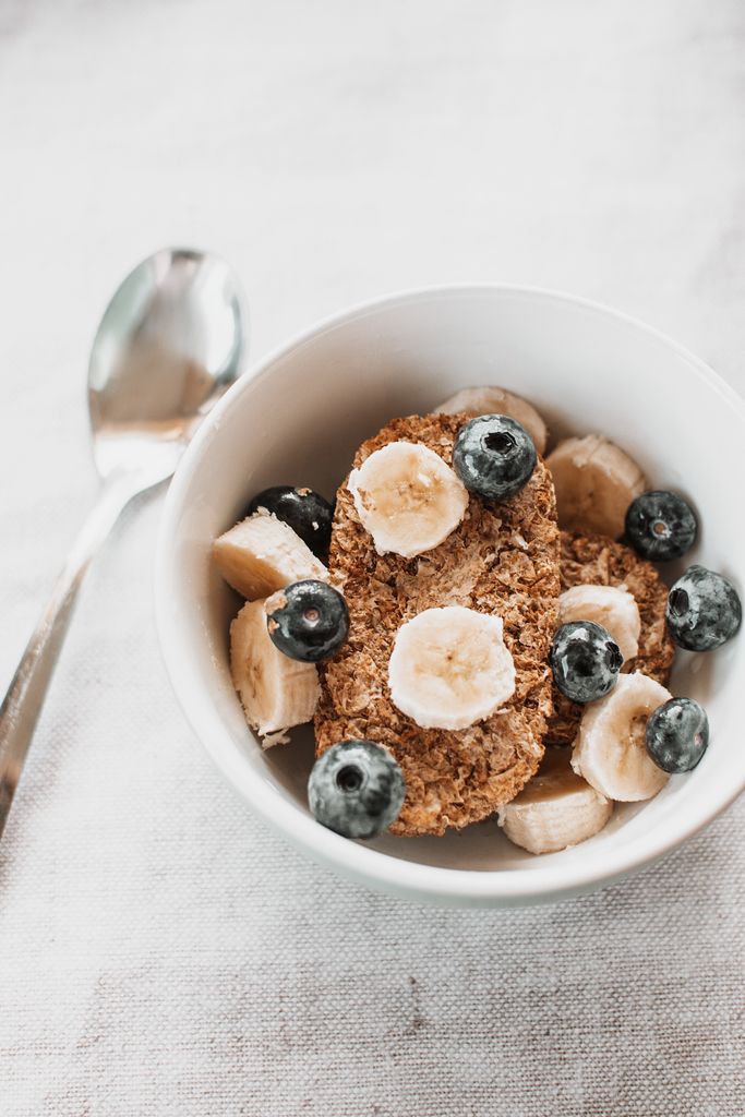 daily habits for better gut health: A healthy cereal breakfast bowl with banana slices and blueberries.