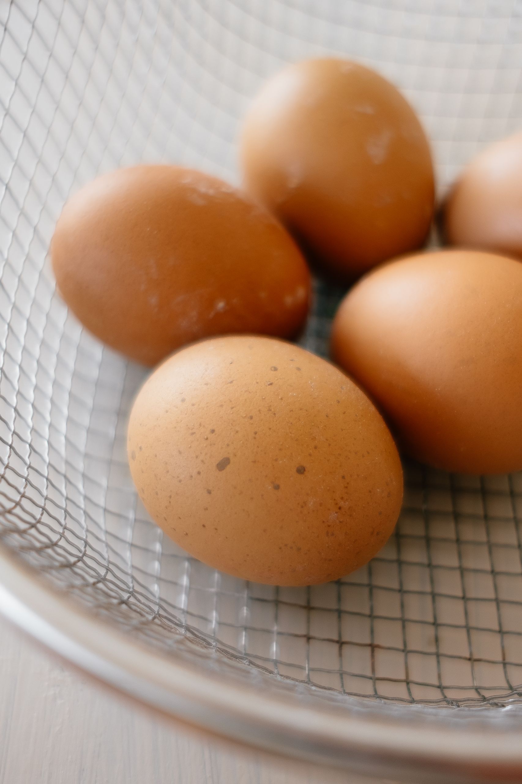 Best Foods for Muscle Gain: Close-up of fresh brown eggs in a wire sieve, perfect for cooking and baking.