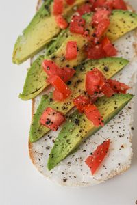 Best Foods for Muscle Gain: Delicious avocado toast topped with tomatoes and black pepper on a white bread slice.