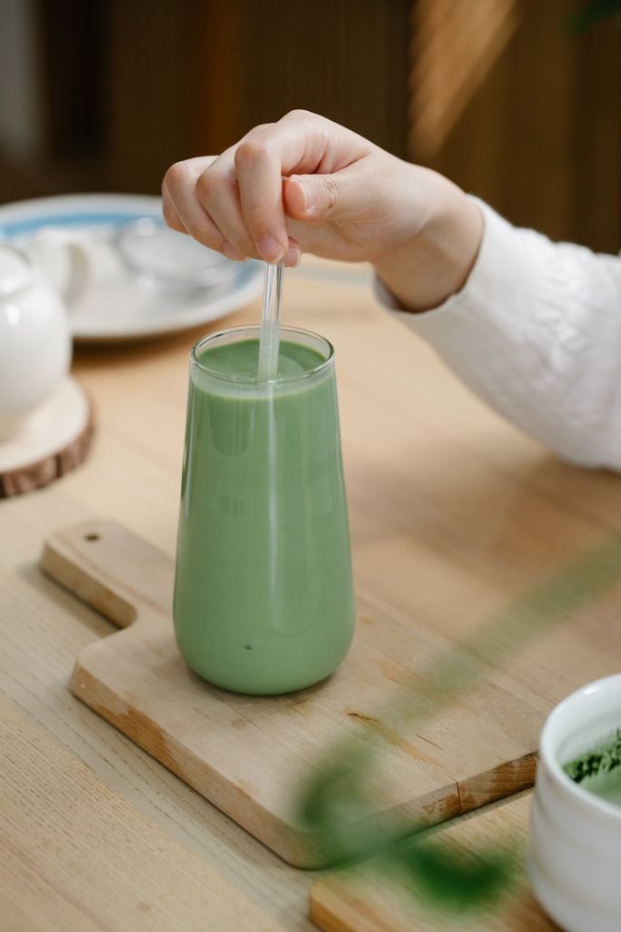 are greens powders worth it: A hand stirs a refreshing iced matcha latte, showcasing an inviting beverage moment.