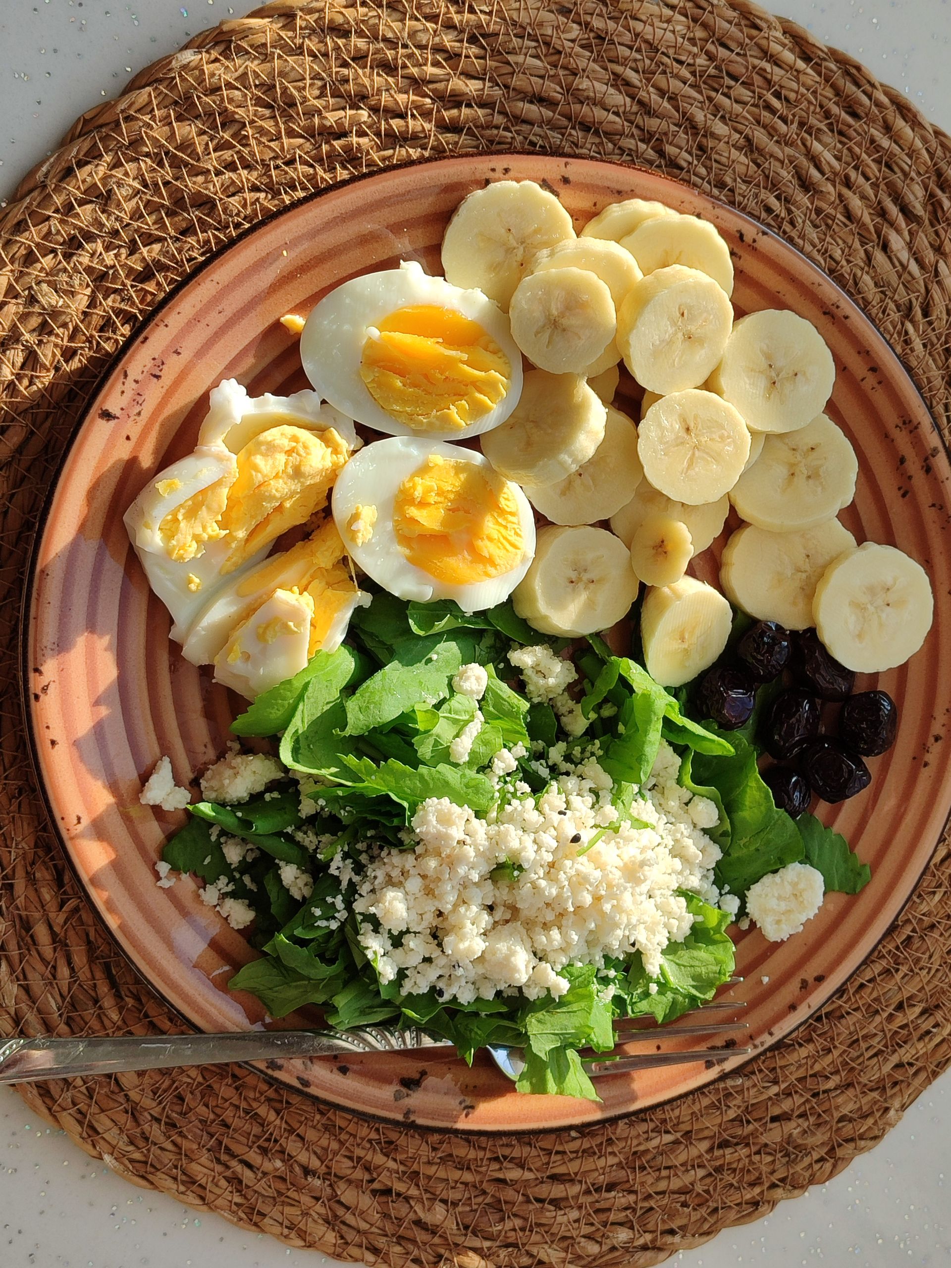how to get enough protein on wegovy: Delicious breakfast with boiled eggs, bananas, greens, and olives on a woven placemat.