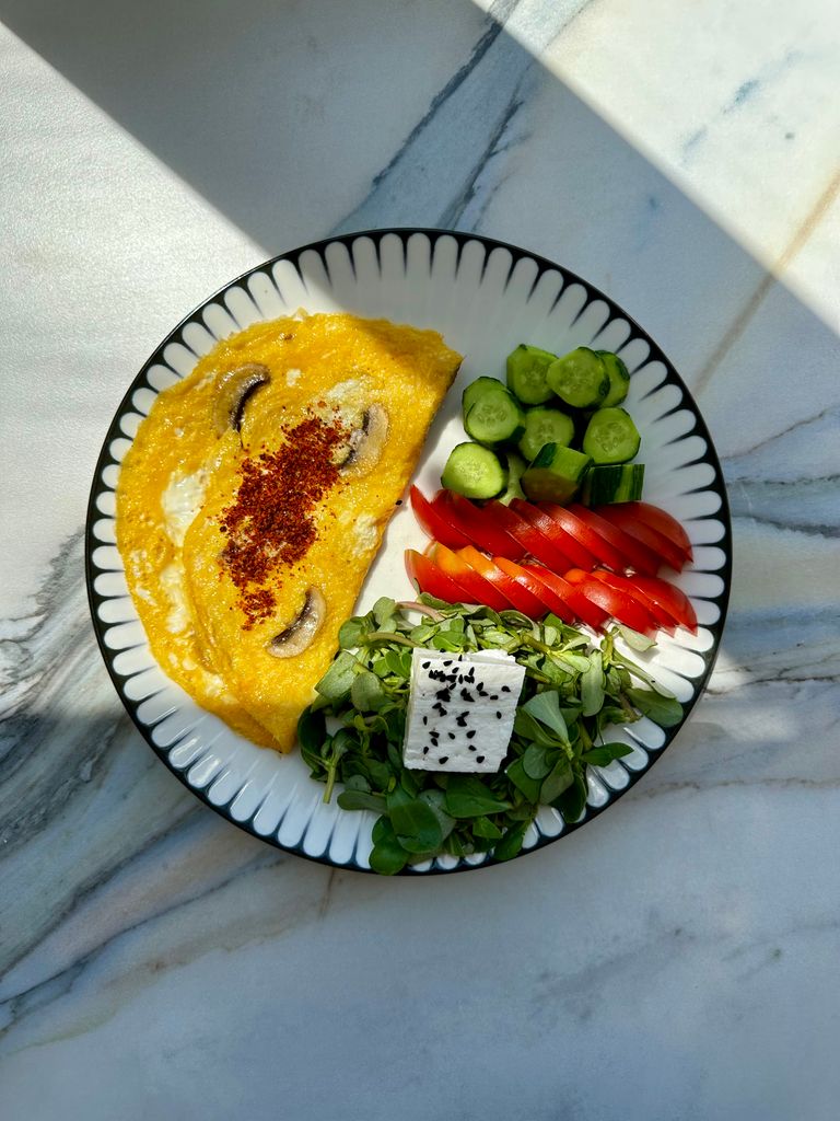 how to get enough protein on wegovy: Delicious omelette with feta, tomatoes, cucumbers, and greens on a white plate.