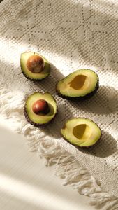 avocado nutrition: Fresh halved avocados displayed on a sunlit, textured cloth perfect for culinary presentations.