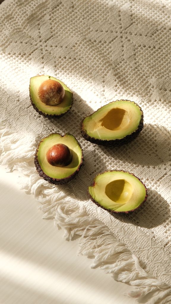 avocado nutrition: Fresh halved avocados displayed on a sunlit, textured cloth perfect for culinary presentations.