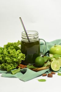 are greens powders worth it: Refreshing green juice with apples, lime, lettuce, and almonds on a wooden board.