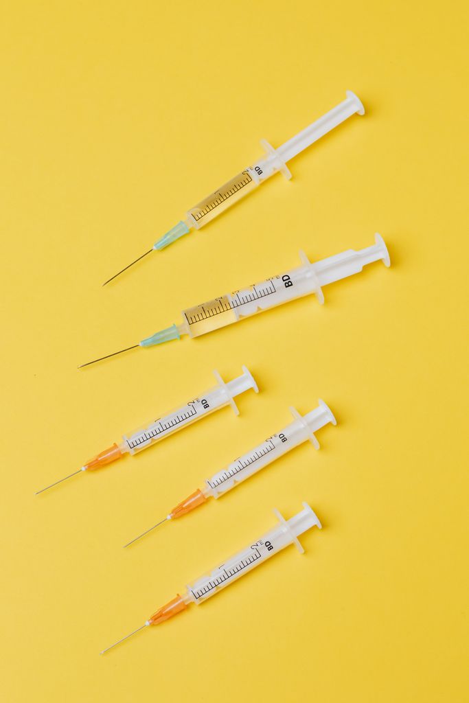not losing weight GLP-1: Top view arrangement of medical single use syringes with vaccine and small empty syringes without needle cover placed on yellow surface