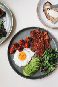 how to get enough protein on Ozempic: Top view of a delicious and healthy breakfast featuring avocado, eggs, bacon, and tomatoes.