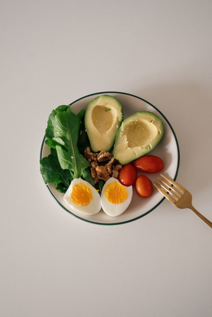 how to get enough protein on Ozempic: Top view of a nutritious plate with avocado, eggs, nuts, and tomatoes.
