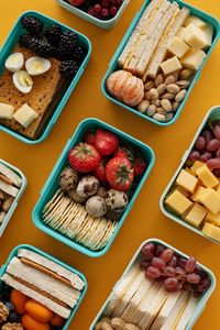 Best Vegetarian Lunches for Work: Top view of diverse snacks in bento boxes on yellow background.