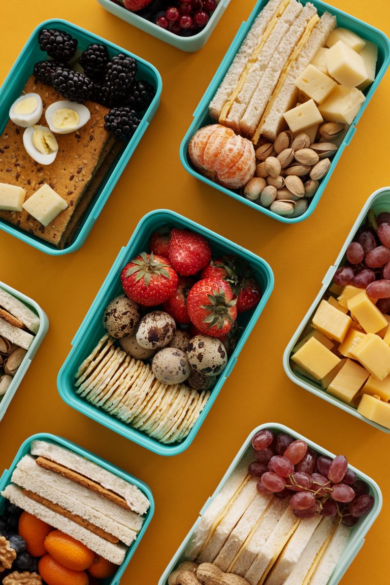 Best Vegetarian Lunches for Work: Top view of diverse snacks in bento boxes on yellow background.